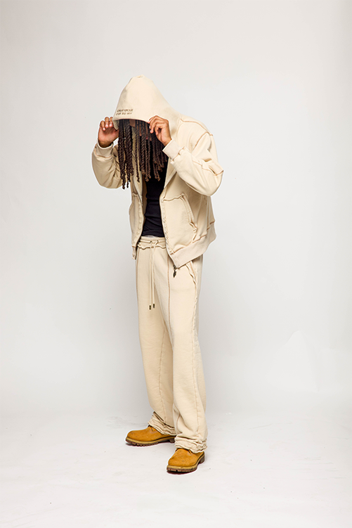 Person wearing a beige hoodie and pants with a plain background